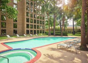 a swimming pool with lounge chairs and a building at DoubleTree by Hilton Houston Intercontinental Airport in Houston