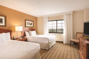 a hotel room with two beds and a flat screen tv at Embassy Suites Greenville Golf Resort & Conference Center in Greenville