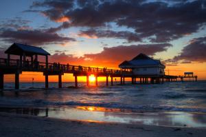 a pier on the beach with a sunset in the background at The Avalon in Clearwater