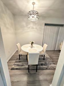 a white dining room table with chairs and a chandelier at The Avalon in Clearwater