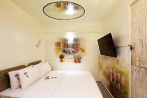 un pequeño dormitorio con una cama blanca y una pintura en Amant Hotel, en Goyang