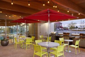un restaurante con mesas, sillas amarillas y una sombrilla roja en Home2 Suites by Hilton Idaho Falls, en Idaho Falls