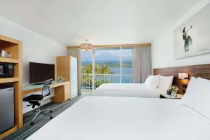 una camera d'albergo con due letti e una televisione di Grand Naniloa Hotel, a Doubletree by Hilton a Hilo