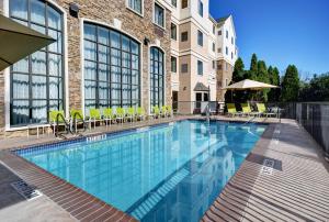 a swimming pool with chairs and a building at Homewood Suites by Hilton Eatontown in Eatontown