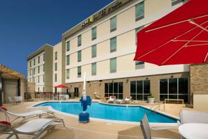 une piscine avec des chaises et un parasol rouge dans l'établissement Hampton Inn by Hilton Hattiesburg, à Hattiesburg