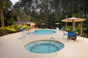 uma piscina com uma mesa e cadeiras e um guarda-sol em Homewood Suites Jacksonville Deerwood Park em Jacksonville