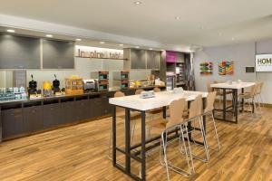 un restaurante con mesas y sillas blancas y una barra en Home2 Suites by Hilton Downingtown Exton Route 30 en Downingtown
