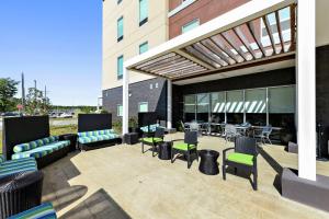 eine Terrasse mit Stühlen und Tischen in einem Gebäude in der Unterkunft Home2 Suites by Hilton Gulfport I-10 in Gulfport