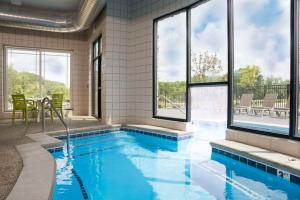 a swimming pool in a house with windows at Hilton Garden Inn Grand Rapids East in Grand Rapids