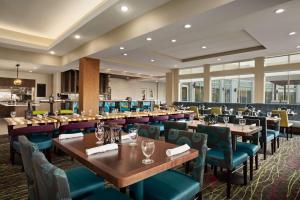 a restaurant with wooden tables and blue chairs at Hilton Garden Inn Houston-Baytown in Baytown