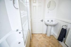 a white bathroom with a shower and a sink at Fitzwilliam House -3 Bed House in Redcar