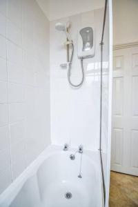 a white bathroom with a tub and a shower at Fitzwilliam House -3 Bed House in Redcar