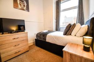 a bedroom with a bed and a dresser with a television at Fitzwilliam House -3 Bed House in Redcar