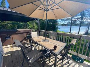 a table and chairs with an umbrella on a deck at Lake Orignal Waterfront SPA Pool Tremblant SKI in Val-des-Lacs