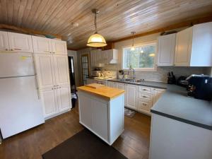 cocina con electrodomésticos blancos y techo de madera en Lake Orignal Waterfront SPA Pool Tremblant SKI, en Val-des-Lacs