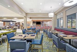 a dining room with tables and blue chairs at Hilton Garden Inn Houston Hobby Airport in Houston
