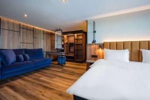 فندق راديسون بلو رويال غاردين، تروندهايم في تروندهايم: غرفة نوم بسرير كبير وأريكة زرقاء