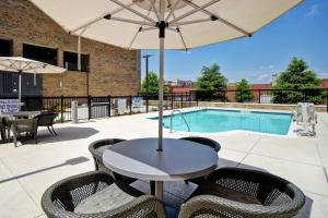 eine Terrasse mit einem Tisch, Stühlen und einem Pool in der Unterkunft Homewood Suites By Hilton Greenville Downtown in Greenville