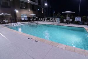 a swimming pool at night with chairs and umbrellas at Hilton Garden Inn Spartanburg in Spartanburg