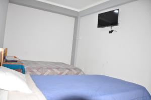 - une chambre avec un lit et une télévision murale dans l'établissement Makalu Lodge, à Huaraz