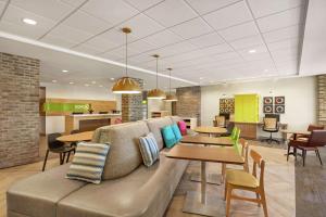a living room with a couch and tables and chairs at Home2 Suites By Hilton Fernandina Beach on Amelia Island, FL in Fernandina Beach