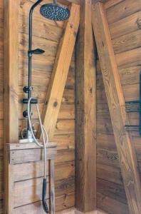 a shower in a room with a wooden wall at Sizo Treehouse Cottage in Roseau +9 photos