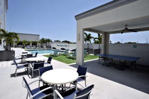 eine Terrasse mit Tischen und Stühlen neben einem Pool in der Unterkunft Hotel Dello Ft Lauderdale Airport, Tapestry Collection by Hilton in Dania Beach