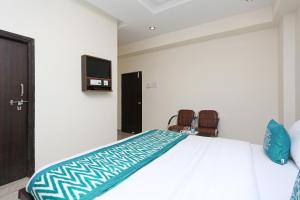 a bedroom with a bed with a tv and two chairs at OYO Flagship Hotel DS Grand Inn in Lingampalli