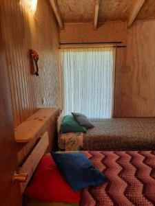 a small room with two beds and a window at Cabañas Volcán Dormido, Hornopirén in Hornopiren