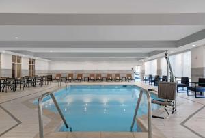 uma piscina no átrio do hotel com cadeiras e mesas em Homewood Suites By Hilton Edison Woodbridge, NJ em Edison