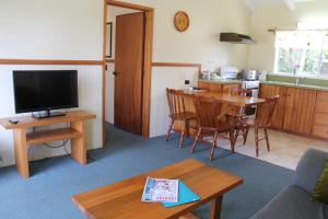 un soggiorno con TV e tavolo e una cucina di Saints Apartment - Free unlimited WIFI a Burnt Pine
