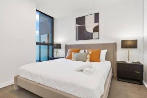 een slaapkamer met een groot wit bed met oranje kussens bij Breathtaking City & River Views HUGE Balcony! in Melbourne
