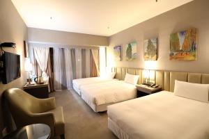 um quarto de hotel com duas camas e uma televisão em Kaohsiung Ahotel em Kaohsiung