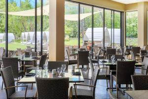 a dining room with tables and chairs and windows at Courtyard by Marriott King Kamehameha's Kona Beach Hotel in Kailua-Kona