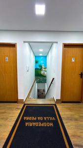 a hallway with two doors and a welcome mat at Apartamentos a 200m do centro - Hospedaria Villa da Pedra in Tiradentes