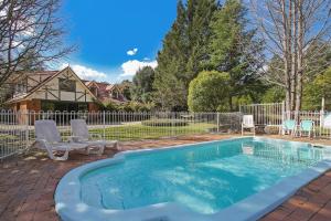 a swimming pool with two chairs and a fence at Plum Pines Bright in Bright