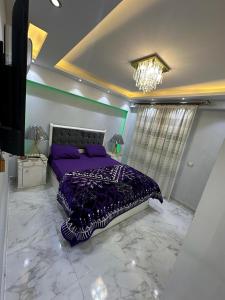 - une chambre avec un lit violet et un lustre dans l'établissement شقة مفروشة للايجار بالمهندسين, au Caire