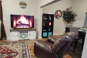 - un salon avec un canapé en cuir et une télévision à écran plat dans l'établissement Downtown Charm Two Bedroom Home, à Noblesville