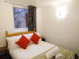 a bedroom with a bed with red pillows and a window at Park Lane Ground Floor Apartment - Workington Town Centre Location - Free Overnight parking in Workington