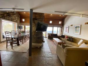 sala de estar con sofá, TV y mesa en Alpine Woodsmoke Apartments en Falls Creek