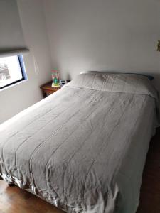 a bed with a gray comforter in a bedroom at La Cortesana in Mexico City