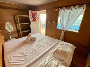 a bedroom with a white bed and a window at Eco Hostal Estrella De Mar in Isla Mucura