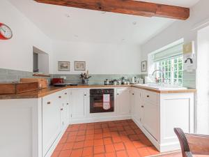 a kitchen with white cabinets and an orange tile floor at Middle Cottage in Letheringsett