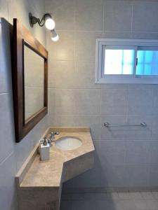een badkamer met een wastafel, een spiegel en een raam bij Departamento perfectamente ubicado in Mendoza