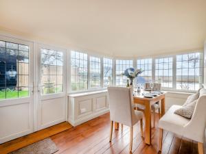 a dining room with a table and chairs and windows at Ship Cottage in Reedham