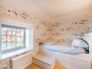 a bed in a room with a wall covered in wallpaper at Ship Cottage in Reedham