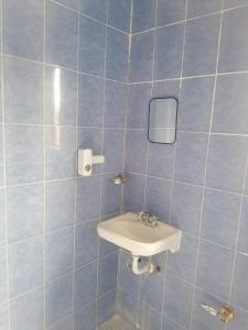 Habitación cómoda para tu estancia, con baño privado في مدينة ميكسيكو: حمام من البلاط الأزرق مع حوض ومرآة