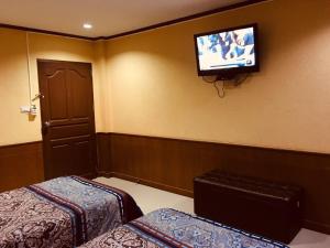 Cette chambre comprend 2 lits et une télévision murale. dans l'établissement จินตคามโฮมเพลส/Jintakam Home Place, à Udon Thani