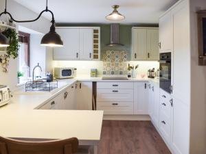 una cocina con armarios blancos y una isla de cocina en Hillview Cottage, en North Nibley