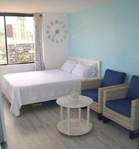 a bedroom with a bed and two chairs and a clock at Hawaiian Monarch 1611 condo in Honolulu